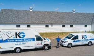 Keith Gauvin standing between two work vehicles